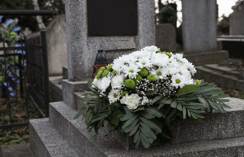 Een wit boeket bloemen op een grafzerk op een kerkhof.